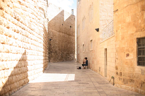 A dimly lit tavern corner where a guide strums a lute, singing softly as shadows dance around.