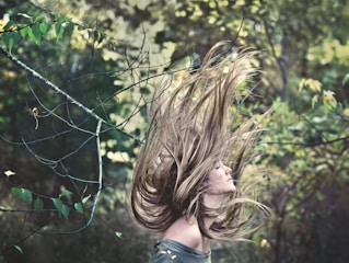 Shiny, healthy hair flowing in natural sunlight with green leaves around.