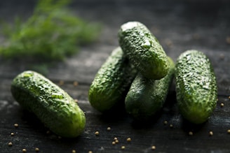 3 green cucumbers on black wooden table
