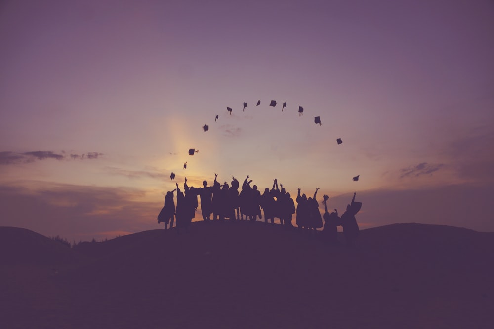 silhouette of people standing on hill