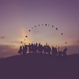 silhouette of people standing on hill