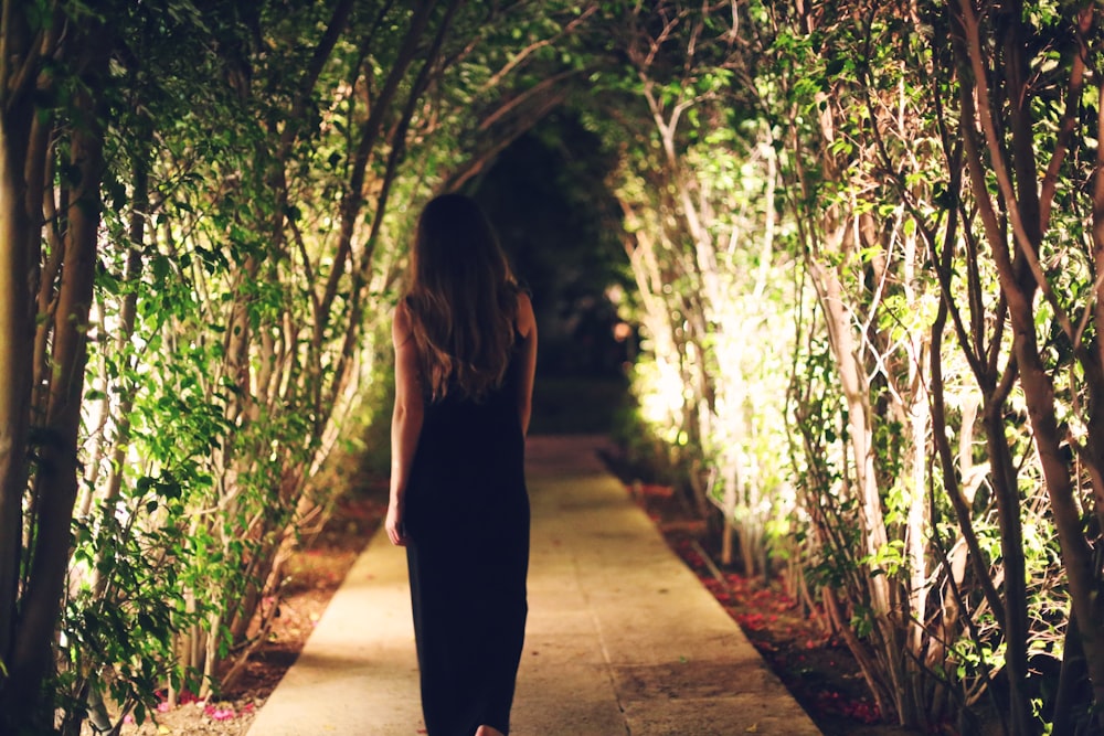 woman walking under green leaf trees