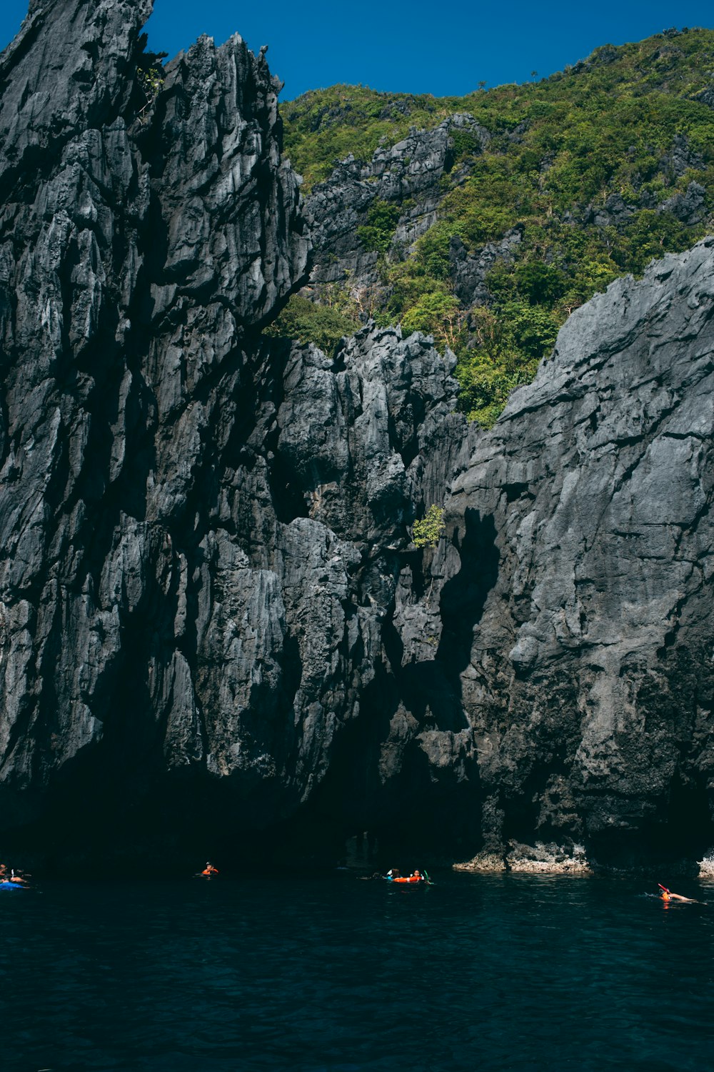 people on sea outside rock cave