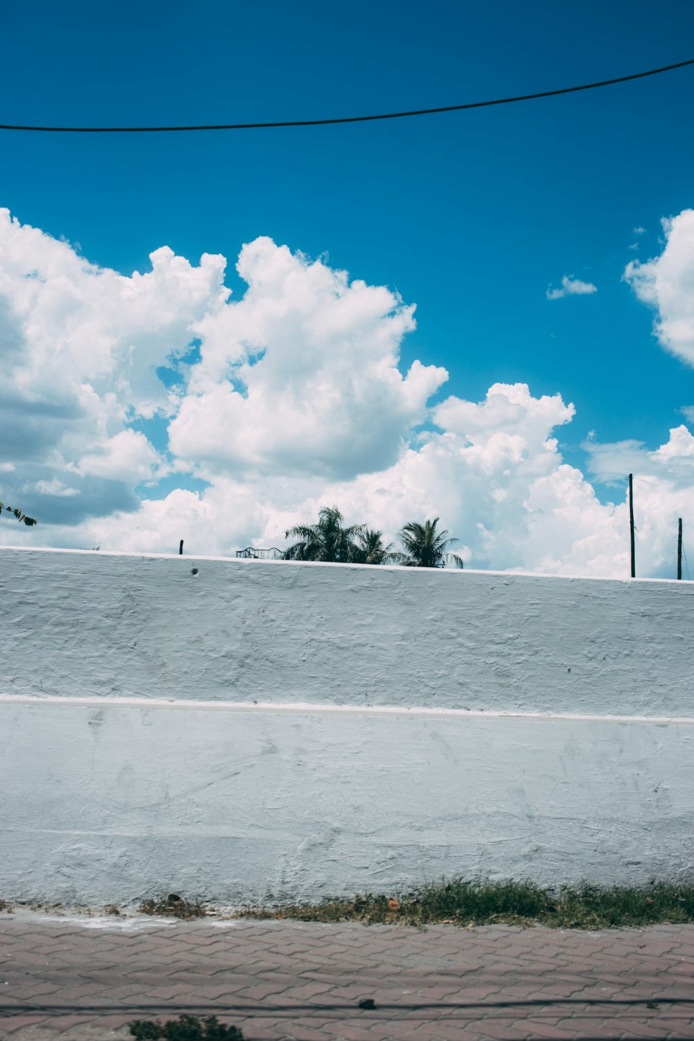 昼間の白い雲と青い空の下に白いコンクリートの壁