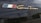 A close-up view of a logo with three vertical stripes in blue, white, and red next to the gold script 'Gran Turismo' on a dark surface.