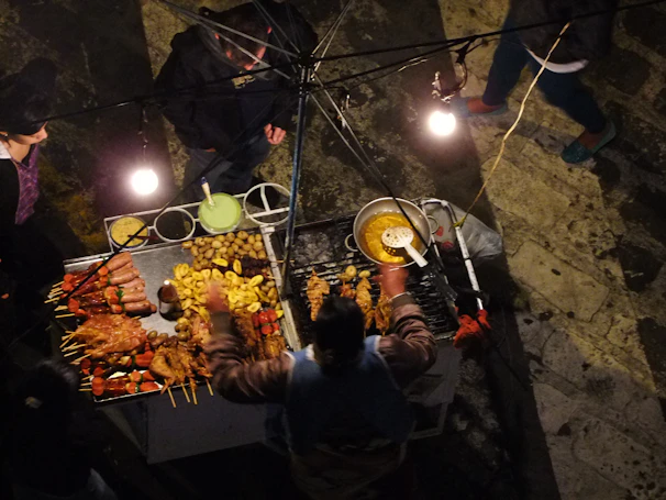 Close-up of a street food vendor serving spicy suya to excited festival-goers.