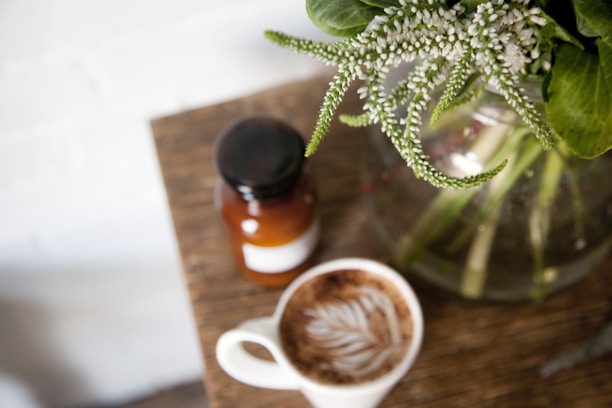 Close-up of a sleek wooden coffee table with a vase of fresh flowers on top.