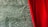 A luxurious deep red velvet curtain partially covers a background of textured green marble. The marble features intricate white veining, adding a sophisticated touch to the scene.