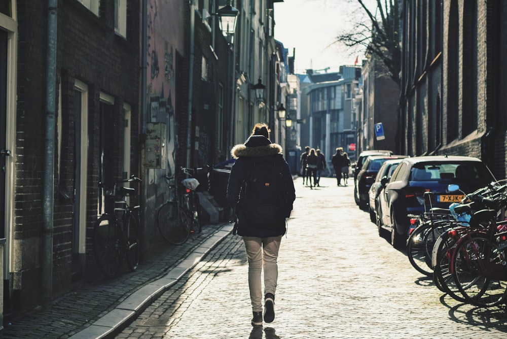 person walking on pathway in between building and parked bicycles at daytime