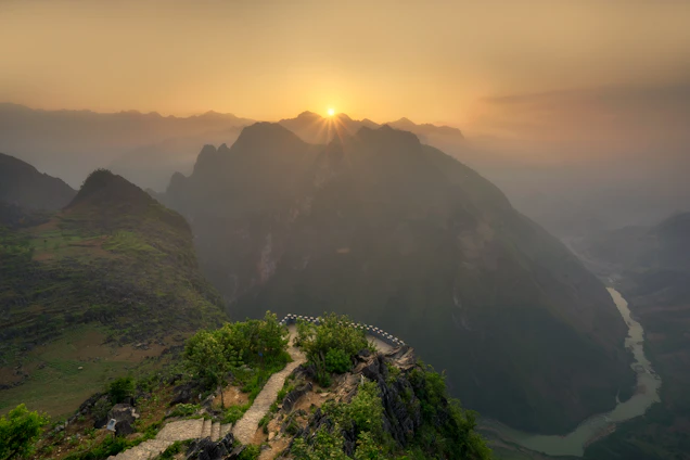 A warm golden sunset over a winding mountain path, inviting travelers to explore.