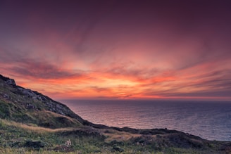 green mountain by the sea during sunset