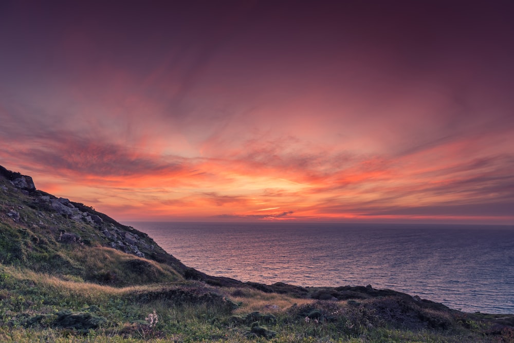 Montagne verte au bord de la mer au coucher du soleil