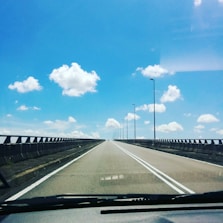 Road view from inside a car showing a clear lane ahead on a bright day.