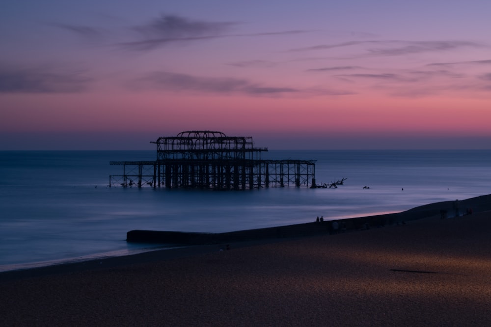 silhouette of structure at shore during sunset