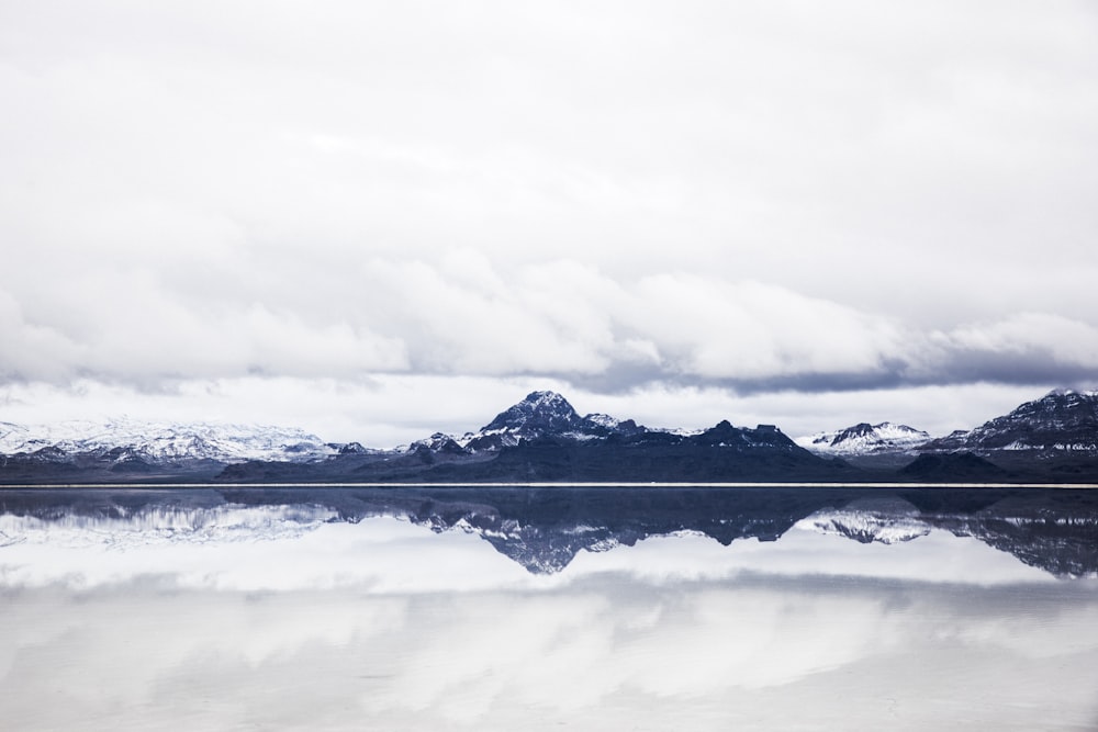 snow capped mountain under white clouds in mirror reflection photography