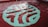 A swimming pool with clear, rippling water reflecting the light. At the bottom, a large, abstract design is visible, featuring a combination of green and aqua hues against a red-tiled background.