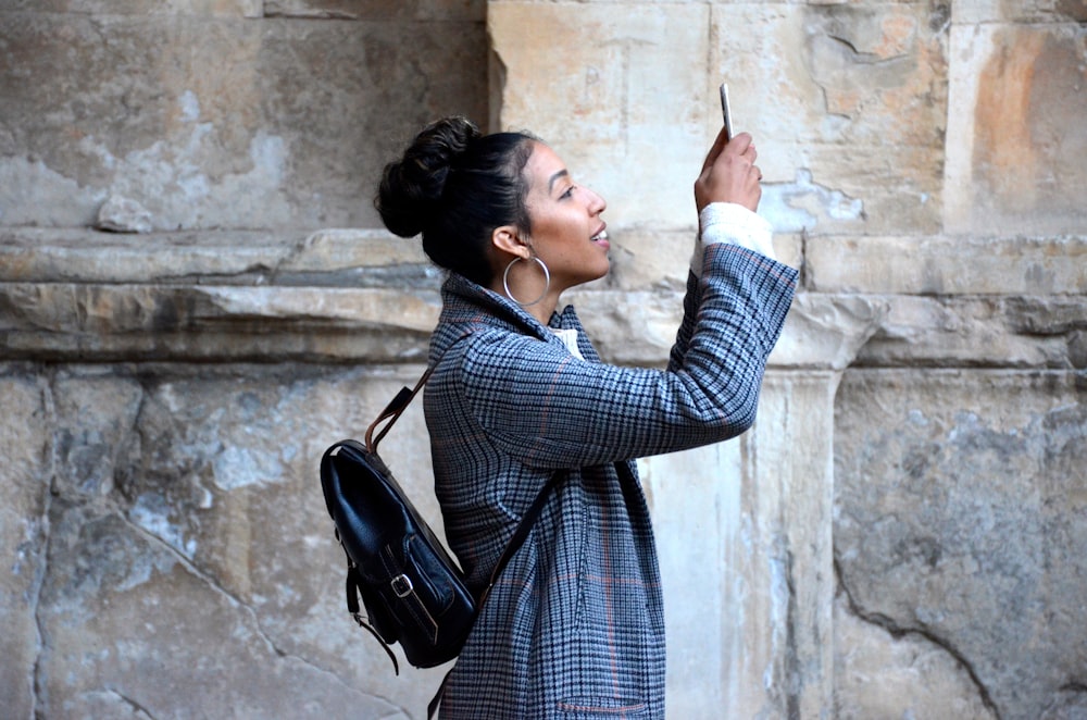 A female tourist smiling while taking a photograph with a smartphone