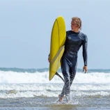 Happy surfer walking out of the water with a neoprene suit