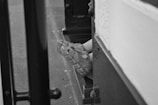 A child's leg wearing a sandal is visible through an opening with a metallic edge. The scene is in black and white, providing a classic and nostalgic feel.