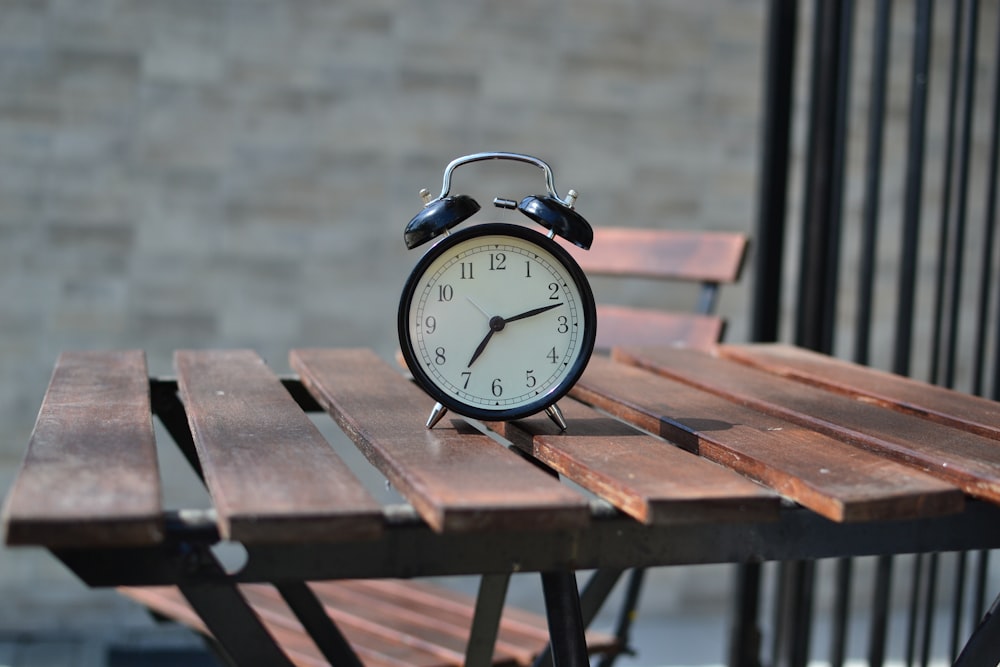 black steel alarm clock on top of brown table