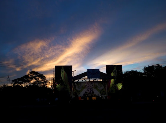 A professional setting up sound and lighting equipment at an event venue during sunset.