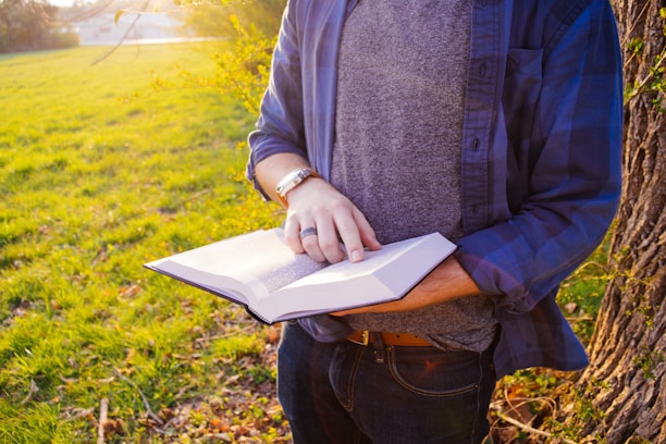 A smiling reader holding a copy of Nonny Mackay's book outdoors on a sunny Texas afternoon.