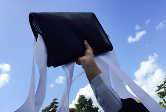 A vibrant illustration of a person joyfully tossing a briefcase into the air against a bright blue sky.