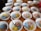 Several white bowls containing colorful shaved ice in shades of blue, pink, and yellow are arranged on a wooden table. Each bowl has a metal spoon resting inside, and the surface of the table is visible between the bowls. The setting appears casual and ready for serving.