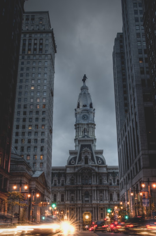 gray concrete building with clock under gray sky in Philadelphia City Hall United States