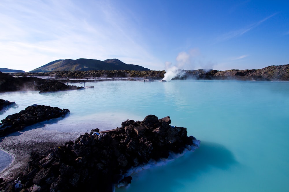 agua tranquila al lado de la montaña bajo nubes blancas y cielo azul