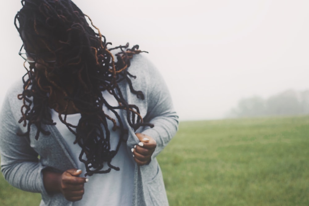 a woman with dreadlocks standing in a field