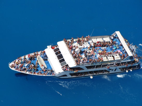 Photo of a lively party boat cruising Miami waters at sunset with guests enjoying food and music on deck.
