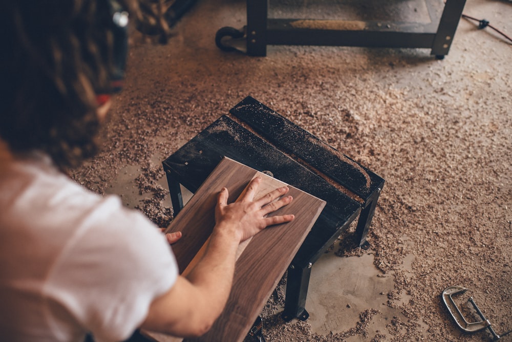 person touching brown plank