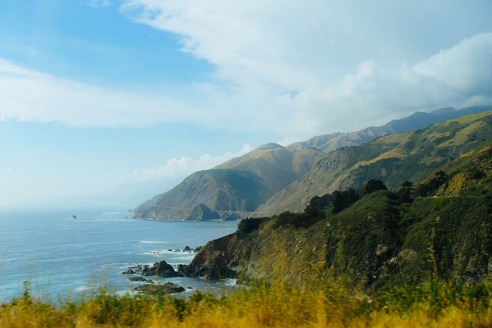 photo of mountains and sea under blue sky