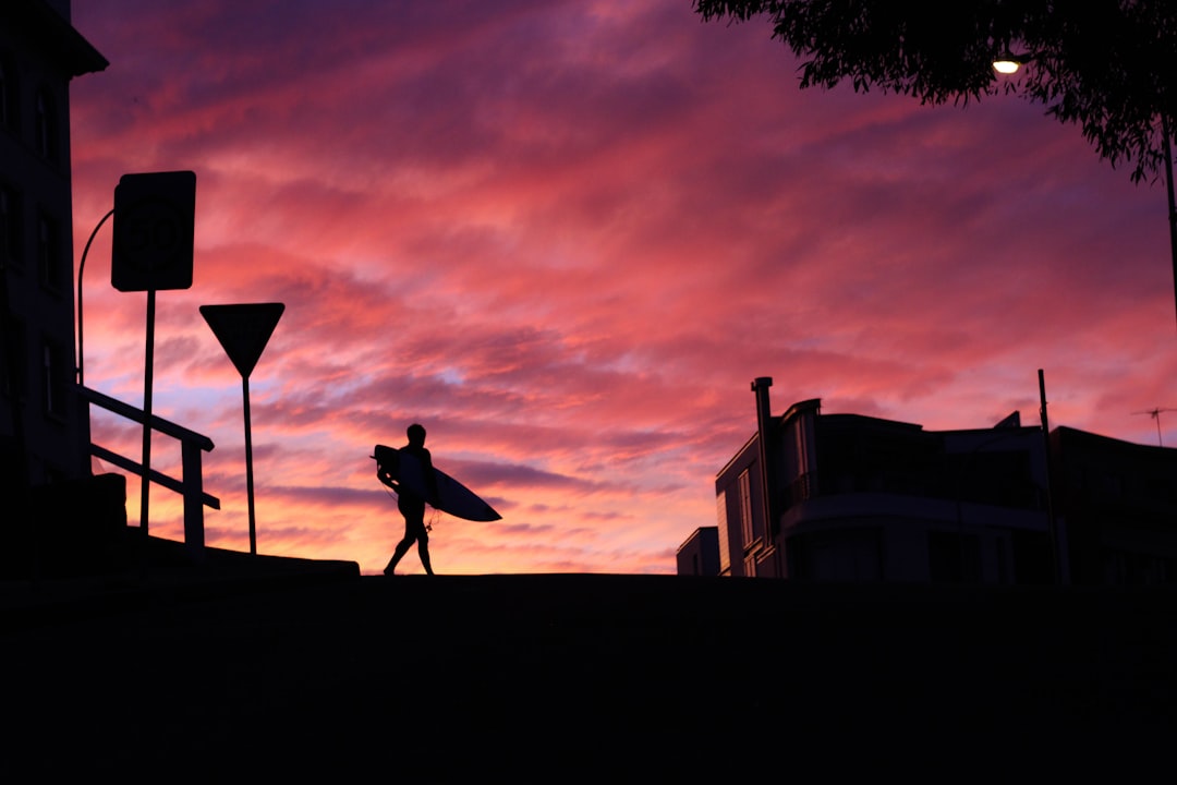 silhouette photography of man walking with a surfboard