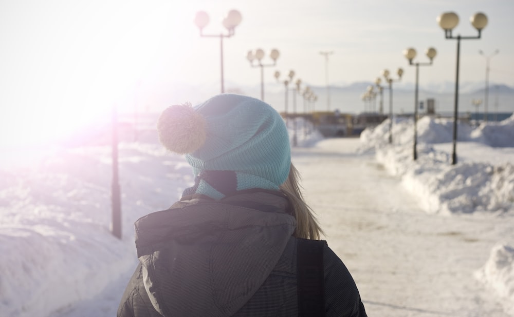 mulher que caminha no caminho coberto de neve durante o dia