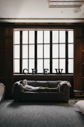 photo of person laying on sofa near window