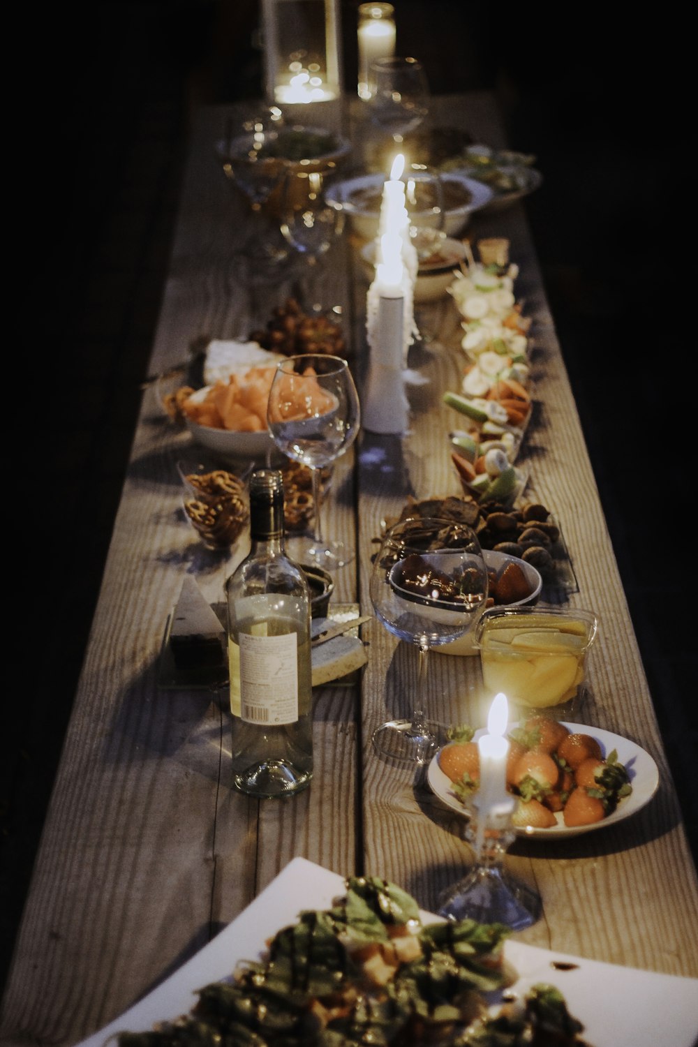 uma longa mesa de madeira com pratos de comida sobre ela