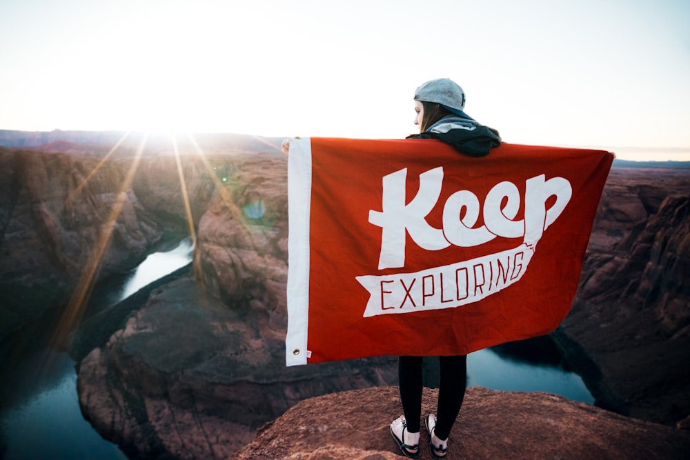 person with banner standing on cliff