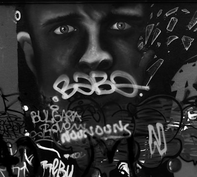 A detailed close-up of layered urban street art with contrasting monochrome and soft grey tones.