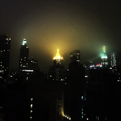 Moody noir-style photo of a city skyline at night with glowing golden highlights
