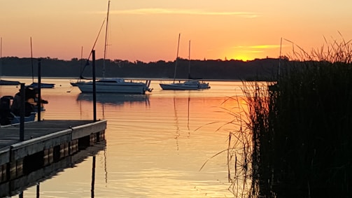 A peaceful sunset over Bear Lake with moored yachts and a welcoming dock.