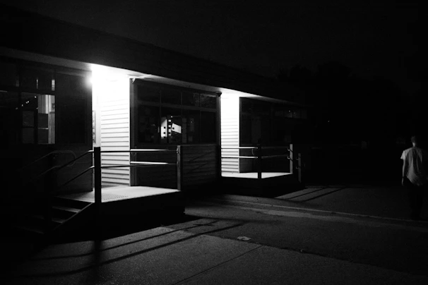 A vigilant security guard monitoring a busy commercial building entrance at dusk.