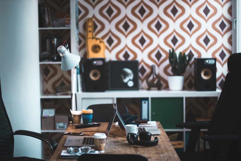 gray laptop computer near black acoustic earmuffs on brown wooden table