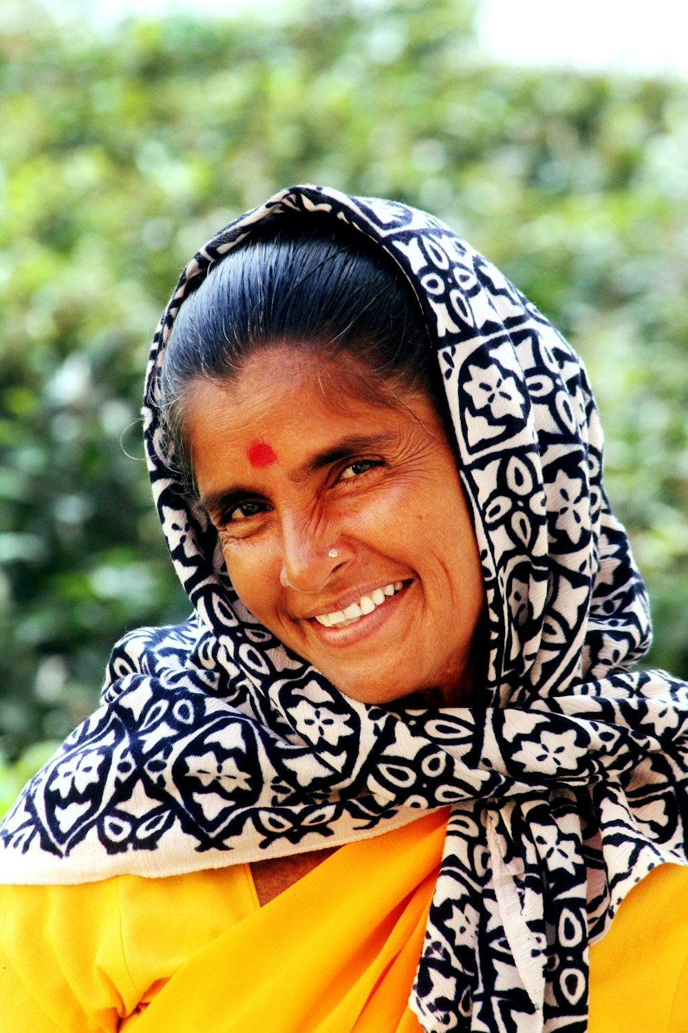 mujer con pañuelo floral blanco y negro mientras sonríe