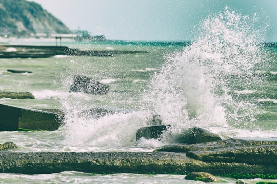 body of water splashing on gray rocks during daytime in Tuapse Russia