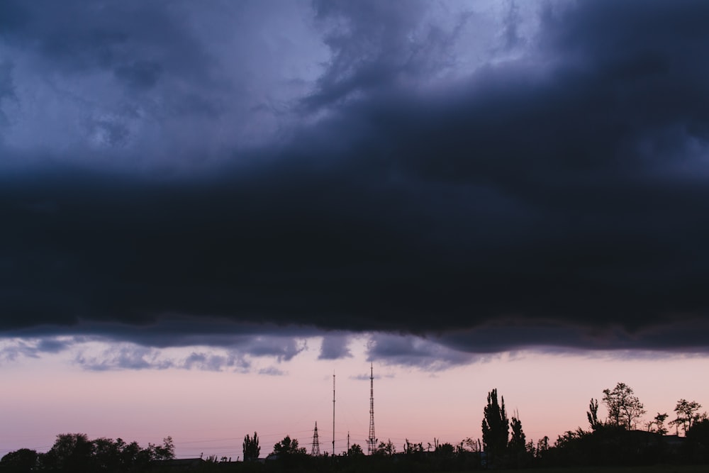 silhouette of trees under cloudy sky