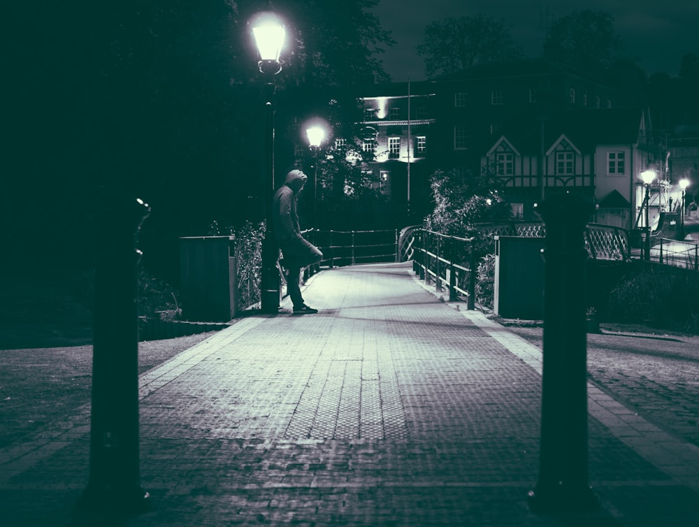 grayscale photo of man leaning on street light