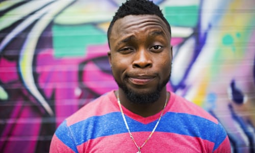 A man making a face, standing in front of graffiti.