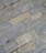 Gray and beige stone tiles laid out in a rectangular brick pattern. The surface appears weathered with some small cracks and variations in texture and color, giving it a rugged and natural appearance.